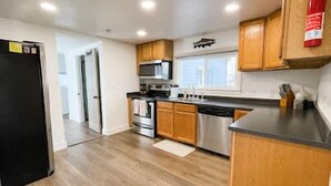 Una cocina moderna con armarios de madera, electrodomésticos de acero inoxidable y un refrigerador negro.
