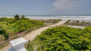 A coastal path leading to the beach with dense greenery and a wooden fence. - Charming Brigantine Condo Rental: Steps to Beach! (Brigantine)