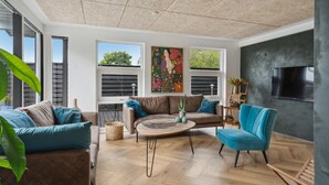 Ein modernes Wohnzimmer mit großem Fenster, Flachbildfernseher und einem Gemälde an der Wand.