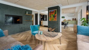 Ein modernes Wohnzimmer mit Fischgrätparkett, einem runden Holztisch und zwei blauen Sesseln.