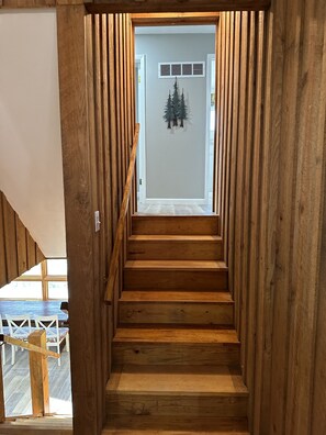 A wooden staircase leading to a room with a white wall and a decorative tree.