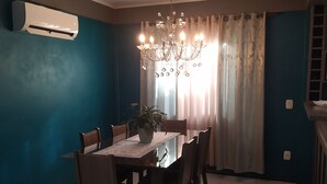 A dining area with a table set for six, surrounded by wooden chairs, a potted plant, and a chandelier. - Aconchego da Família, Excelente Espaço Para Famílias, a 3 Minutos da Rua Coberta (Gramado)