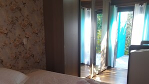 A bedroom with a bed, a pillow, and a rolled towel. There is a sliding glass door leading to an outdoor area. - Aconchego da Família, Excelente Espaço Para Famílias, a 3 Minutos da Rua Coberta (Gramado)