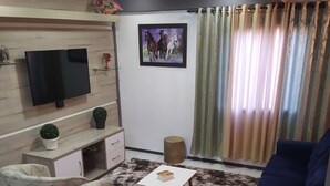 A living room with two armchairs, a sofa, a coffee table, a TV, a small cabinet, a plant, a rug, and a picture on the wall. - Aconchego da Família, Excelente Espaço Para Famílias, a 3 Minutos da Rua Coberta (Gramado)