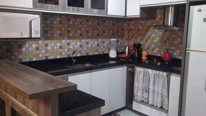 A kitchen with wooden cabinets, a tiled backsplash, a black countertop, a coffee maker, and a kettle. - Aconchego da Família, Excelente Espaço Para Famílias, a 3 Minutos da Rua Coberta (Gramado)