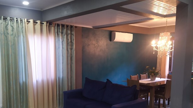 A living room with a blue sofa, two armchairs, a coffee table, and a dining area with a chandelier. - Aconchego da Família, Excelente Espaço Para Famílias, a 3 Minutos da Rua Coberta (Gramado)