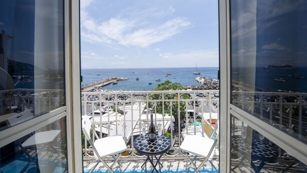 A balcony with a table and chairs, overlooking a marina with boats and a pier.
