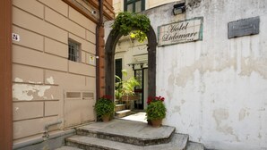 A hotel entrance with a stone staircase, a sign reading "Hotel Lido Mare," and potted plants.