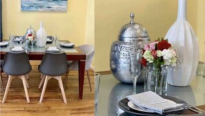 Ein Essbereich mit einem Tisch für zwei Personen, einer Blumenvase und einer dekorativen Silberdose.