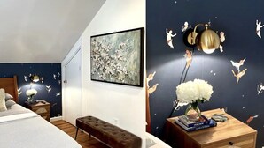 Ein Schlafzimmer mit Bett, Bank, Nachttisch und Wandbildern.