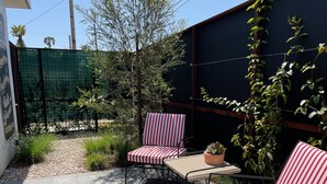 A patio area with two striped chairs, a small table, and a potted plant. - Modern cozy Santa Monica Studio w/ Patio - 18 blocks from the beach! (Santa Monica)