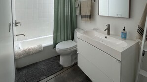 A modern bathroom with a bathtub, toilet, and vanity. - Modern cozy Santa Monica Studio w/ Patio - 18 blocks from the beach! (Santa Monica)
