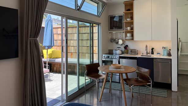 A modern kitchen with a dining area, a large sliding glass door leading to a patio, and a view of the outdoors. - Modern cozy Santa Monica Studio w/ Patio - 18 blocks from the beach! (Santa Monica)