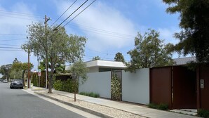 A modern building with a gated entrance, a clear sky, and a street with parked cars. - Modern cozy Santa Monica Studio w/ Patio - 18 blocks from the beach! (Santa Monica)