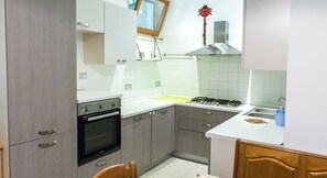 A kitchen with a stove, oven, and sink, wooden cabinets, and a window. - SE009 - Senigallia, three-room apartment on the sea with beach (Senigallia)