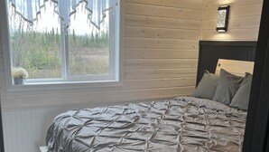 Una camera da letto con un letto, una finestra con tende e un comodino.