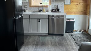 Una cucina moderna con soffitto in legno, elettrodomestici in acciaio inossidabile e una finestra che fa entrare luce naturale.