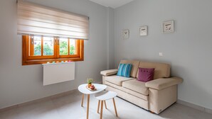 Una sala de estar moderna con un sofá beige, una mesita con una planta y una ventana con persianas.