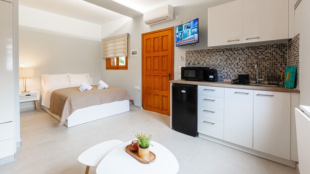 Una habitación de hotel moderna con cama, mesita de noche y un pequeño comedor.