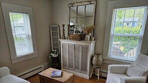 Een woonkamer met een witte bank, een houten salontafel, een witte kast en een grote spiegel.