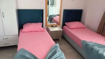 A bedroom with two beds, a nightstand, a mirror, and a wardrobe.