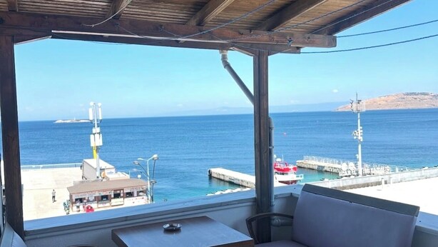 A covered outdoor seating area with a view of the sea and a dock. - Avşa apart otel (Marmara)