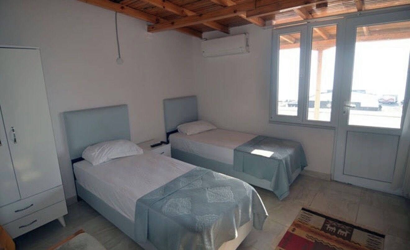 A bedroom with two beds, a wardrobe, and a window with a view.