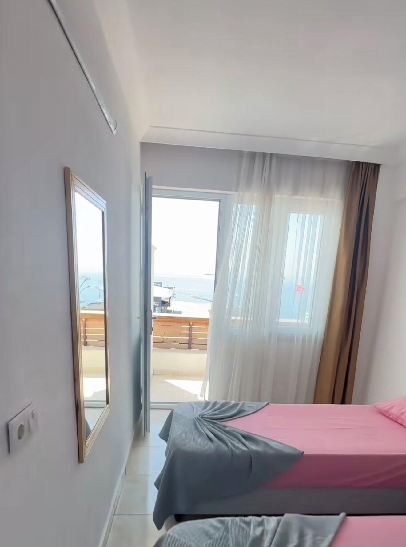 A hotel room with two beds, a large window with curtains, and a view of the outside.