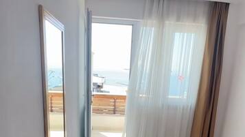 A hotel room with two beds, a large window with curtains, and a view of the outside.