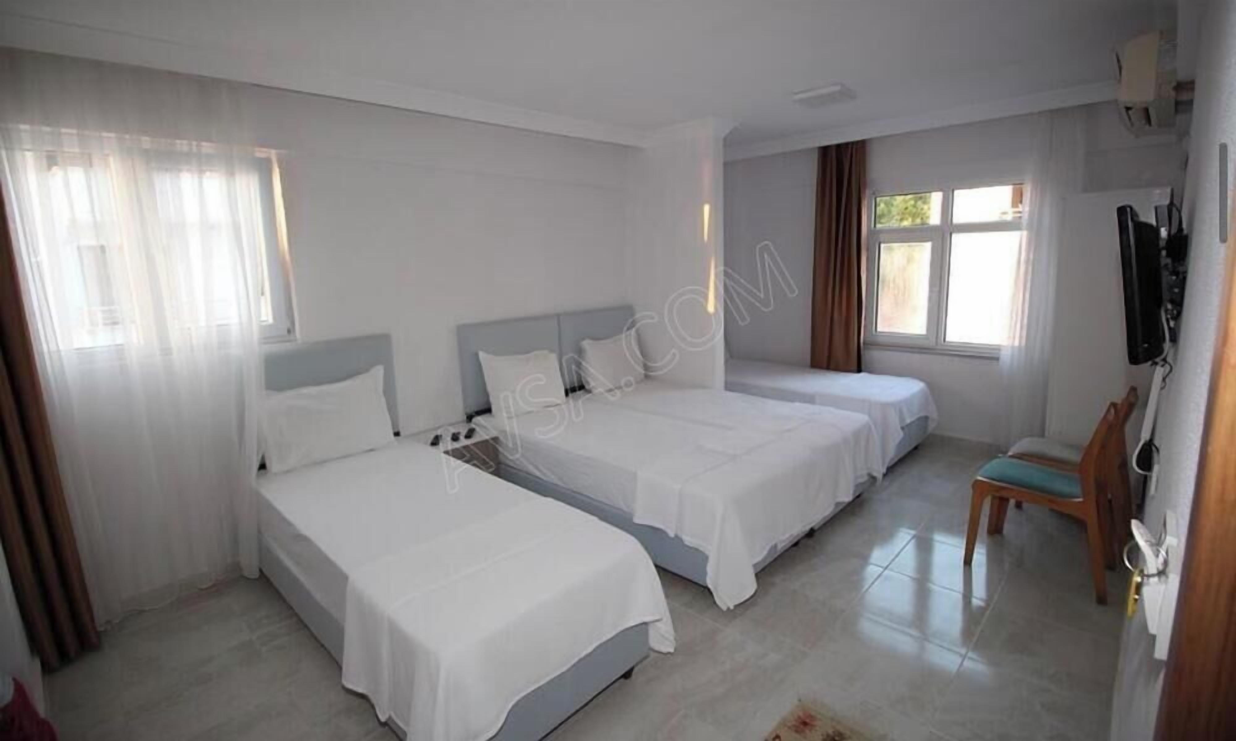 Habitación de hotel con tres camas, un televisor y una silla.