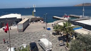 A coastal view with a terminal building, a cafe, and a dock with a boat. - Avşa apart otel (Marmara)