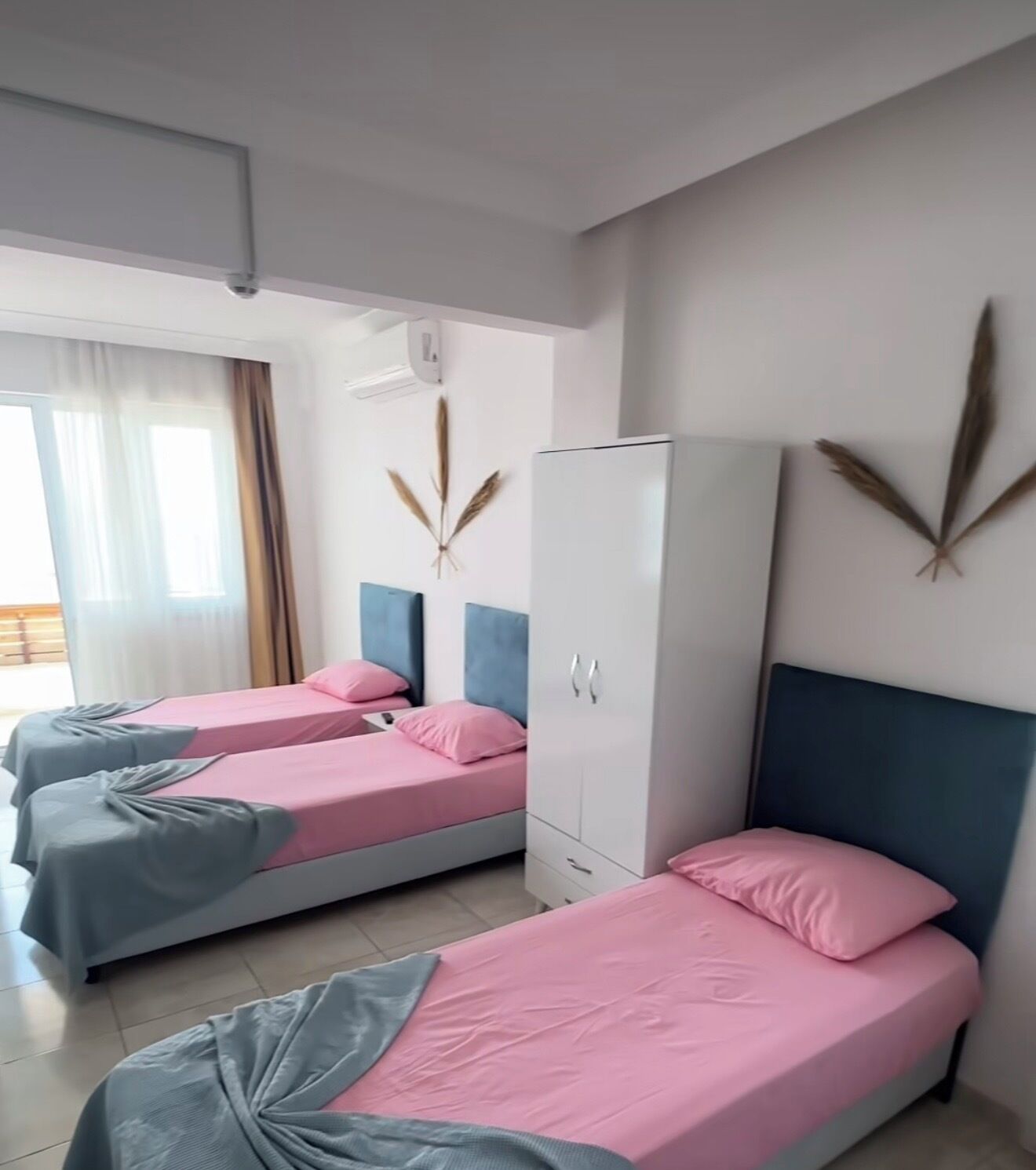 A hotel room with two beds, a wardrobe, and a window with curtains.