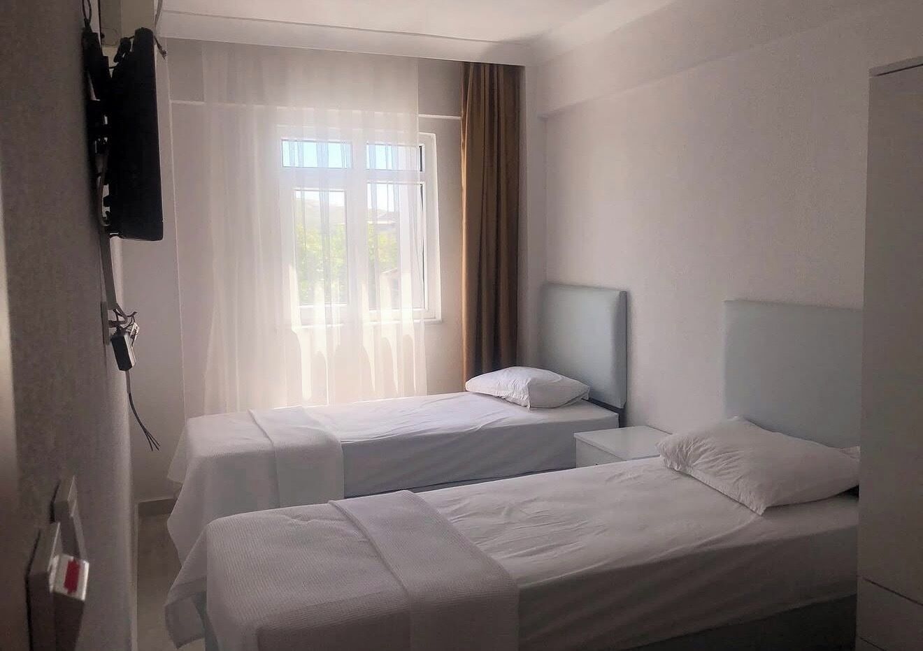 A hotel room with two beds, a TV, and a window with curtains.