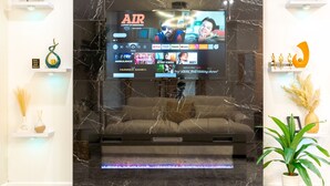 A modern living room with a large flat-screen TV mounted on a wall, a sofa, and a fireplace. - Sovereign Cottage-Parking , Self Check-in  & Wifi (East Orange)