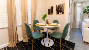 A dining area with a round table, four chairs, and a potted plant. - Sovereign Cottage-Parking , Self Check-in  & Wifi (East Orange)