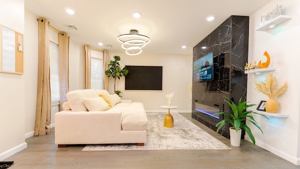 A modern living room with a sofa, TV, and decorative plants. - Sovereign Cottage-Parking , Self Check-in  & Wifi (East Orange)