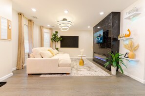 A modern living room with a sofa, TV, and decorative plants.