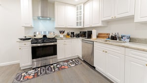 A modern kitchen with white cabinets, stainless steel appliances, and a kitchen island. - Sovereign Cottage-Parking , Self Check-in  & Wifi (East Orange)
