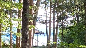 Metsäinen alue, jonka taustalla näkyy huvimajaa muistuttava rakennelma.