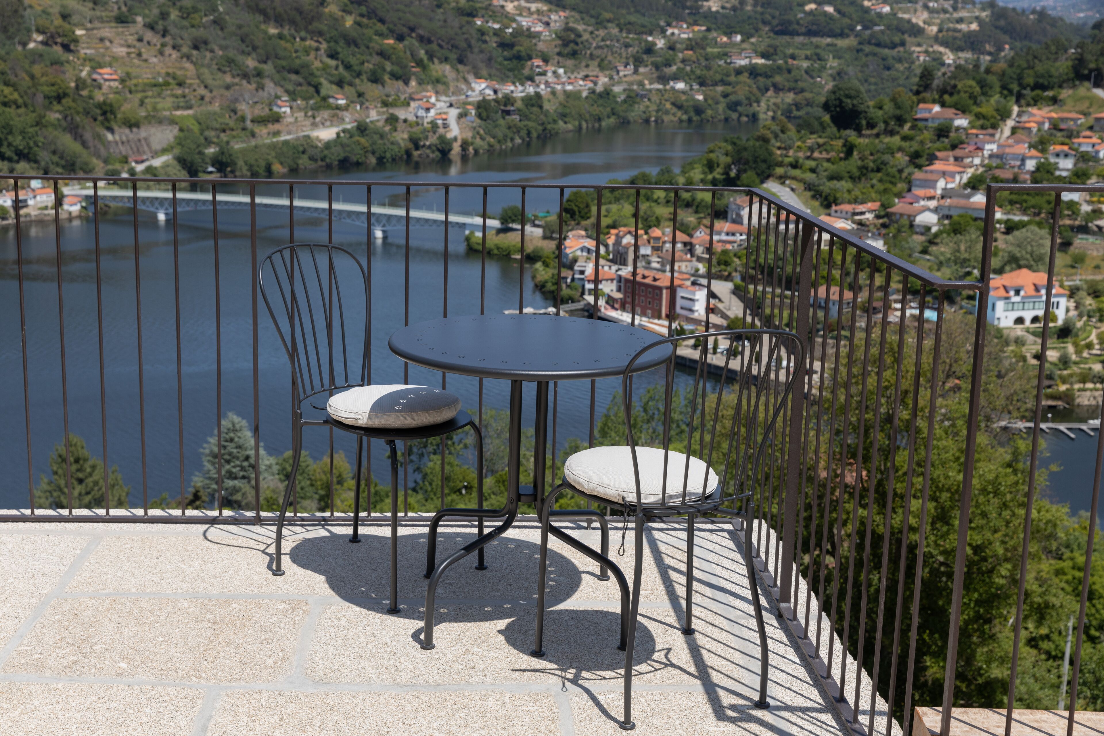 Una terraza con una mesa y dos sillas, con vistas a un río y un pueblo.