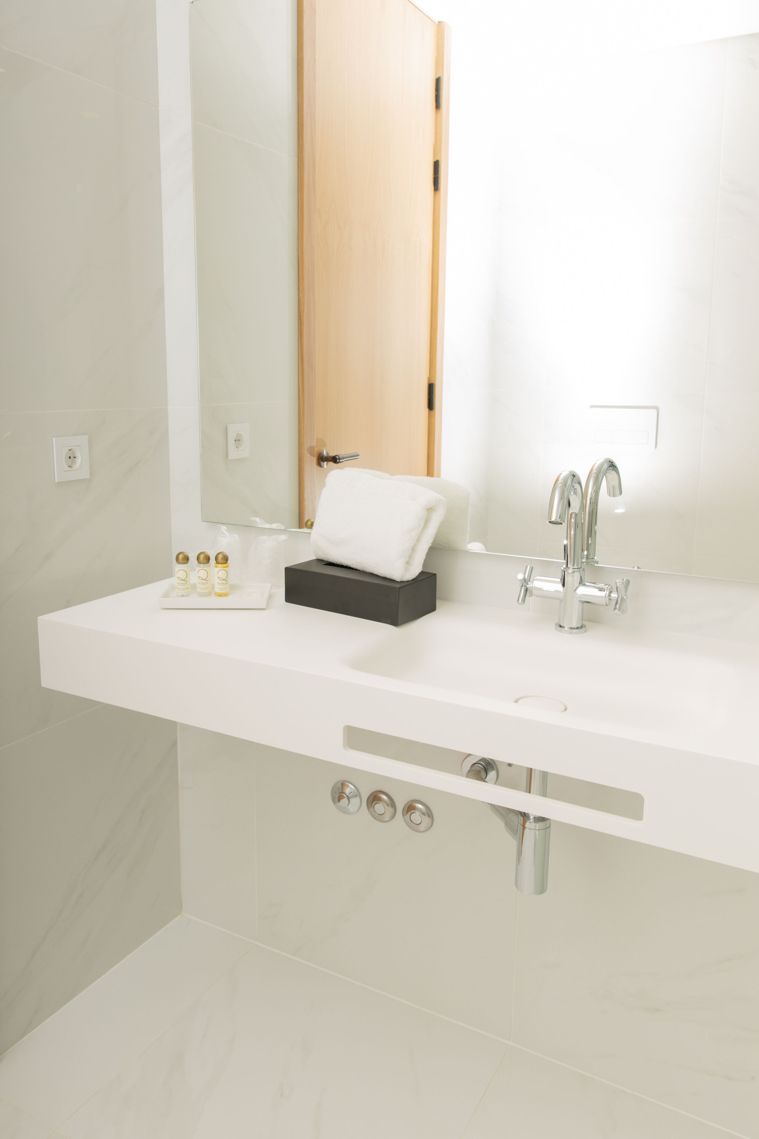 Une salle de bain moderne avec un meuble-lavabo blanc, un grand miroir, une serviette et un lavabo avec un robinet.