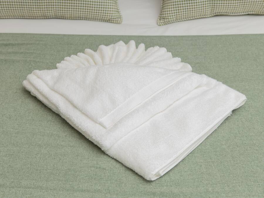 A neatly folded white towel on a green bedspread.