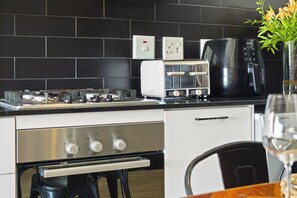 A modern kitchen with a gas stove, built-in oven, toaster, and coffee maker. - Cape on Porterfield 5 (Cape Town)