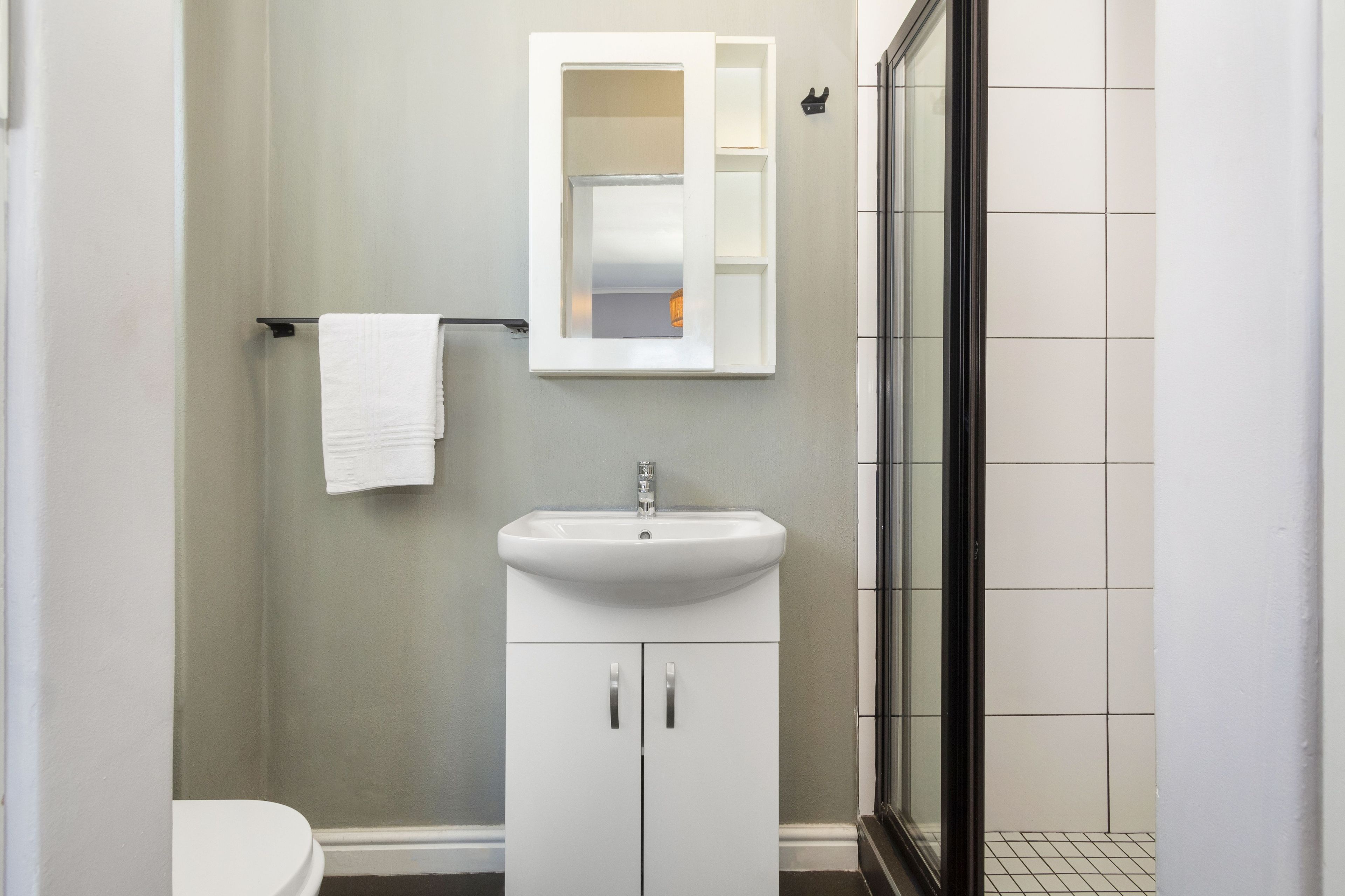 Ein Badezimmer mit Waschbecken, Spiegel und Duschkabine aus Glas.