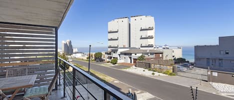 Un balcón con vista a una calle y edificios, incluyendo una estructura alta con balcones.