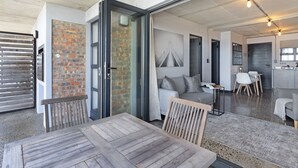 A modern interior with a dining area, a kitchen, and a living space. - Manhattan on Coral 7 (Cape Town)