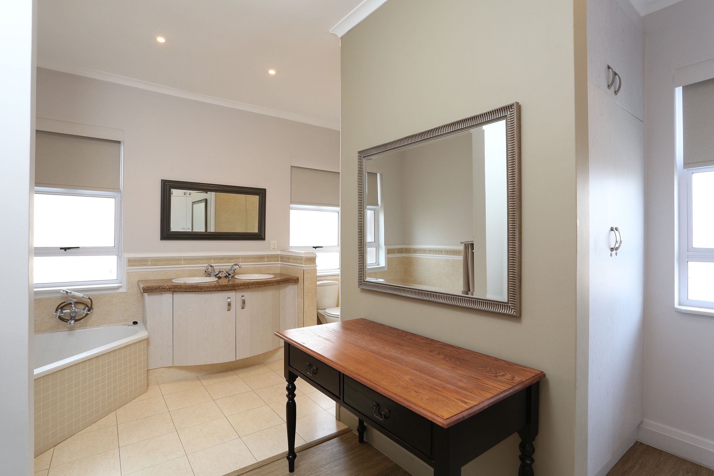 A bathroom with a bathtub, sink, vanity, and a large mirror.