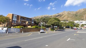 A multi-story building with balconies, a clear road, and mountains in the background. - Summer Place 9 (Cape Town)