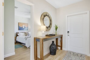 A hotel room with a bed, a bedside table with a lamp, a mirror, and a vase.