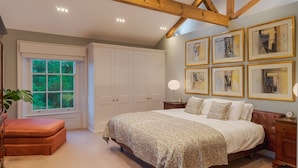 Un dormitorio con una cama grande, una ventana, un armario y cuadros en la pared.